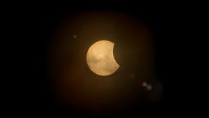 Partial solar eclipse similar to what’s expected during the solar eclipse August 2025, showing the Moon slightly covering the Sun against a dark sky.